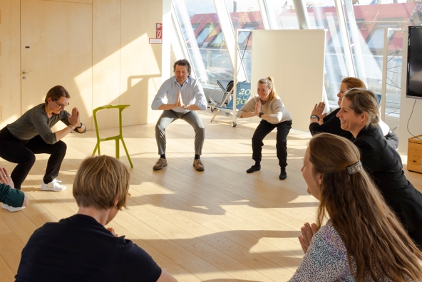 Mitarbeiter*innen gehen in die Hocke bei Bewegungsübungen.