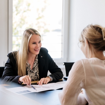 Zwei Frauen unterhalten sich und sehen sich ein Prospekt an
