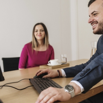 Ein Mann erklärt einer Frau etwas auf einem Computer.
