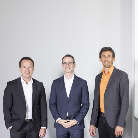 Drei Männer stehen nebeneinander und tragen einen Anzug